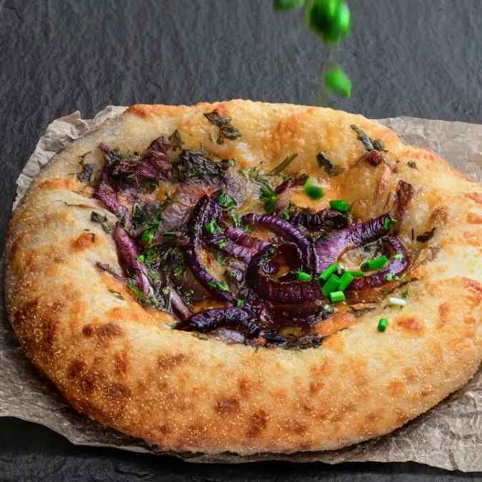 A screenshot of the Shopify admin dashboard displaying the blog post editor. The post is titled 'Red Cheddar & Balsamic Red Onion Flatbread' and shows introductory text about the recipe in the rich text editor.
