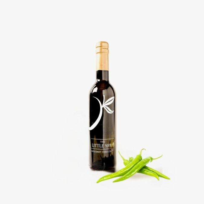 Bottle of Baklouti Pepper Olive Oil with fresh peppers on white background. 