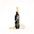 A bottle of gourmet garlic olive oil, styled with fresh garlic cloves and a whole garlic bulb on a clean white background.
