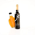 Two bottles from 'The Little Shop Gourmet Essentials' on a white background: a dark glass bottle with a gold foil top and white logo, and a clear glass bottle filled with Vermont maple syrup and a black cap.