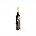 Dark glass bottle of white truffle premium olive oil labeled with 'THE LITTLE SHOP' on a crisp white background with shaved white truffles surrounding the bottle. 