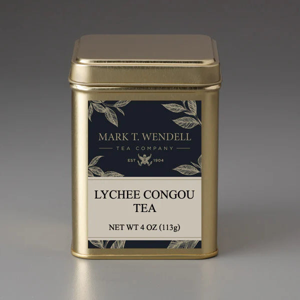 Gold tea canister labeled 'Lychee Congou Tea' by Mark T. Wendell on a gray background