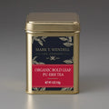 Gold tea canister with a red label on a gray background for Organic Bold Leaf Pu-erh Tea